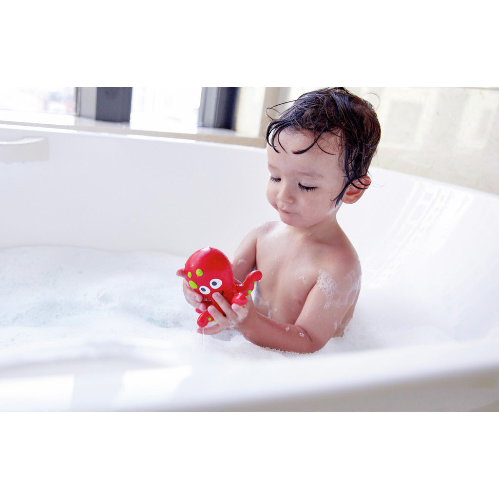 Kleinkind badet mit giftfreiem, nachhaltigem und kindgerechtem Hape Meer-Freunde Spielzeug in weißer Badewanne.