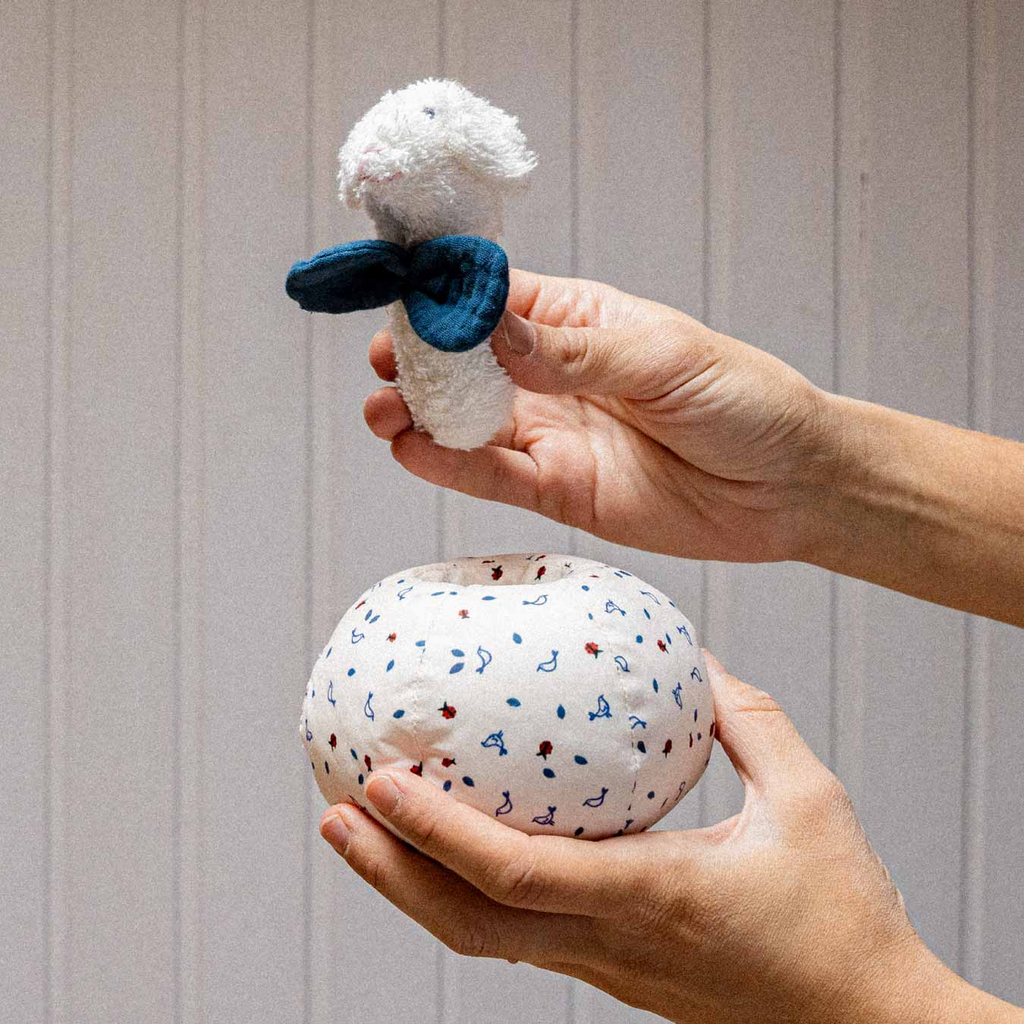 Nachhaltige kindgerechte Lamm-Rassel aus weichem, giftfreiem Material, säuglingstauglich und sicher in weiß mit blauem Schal.
