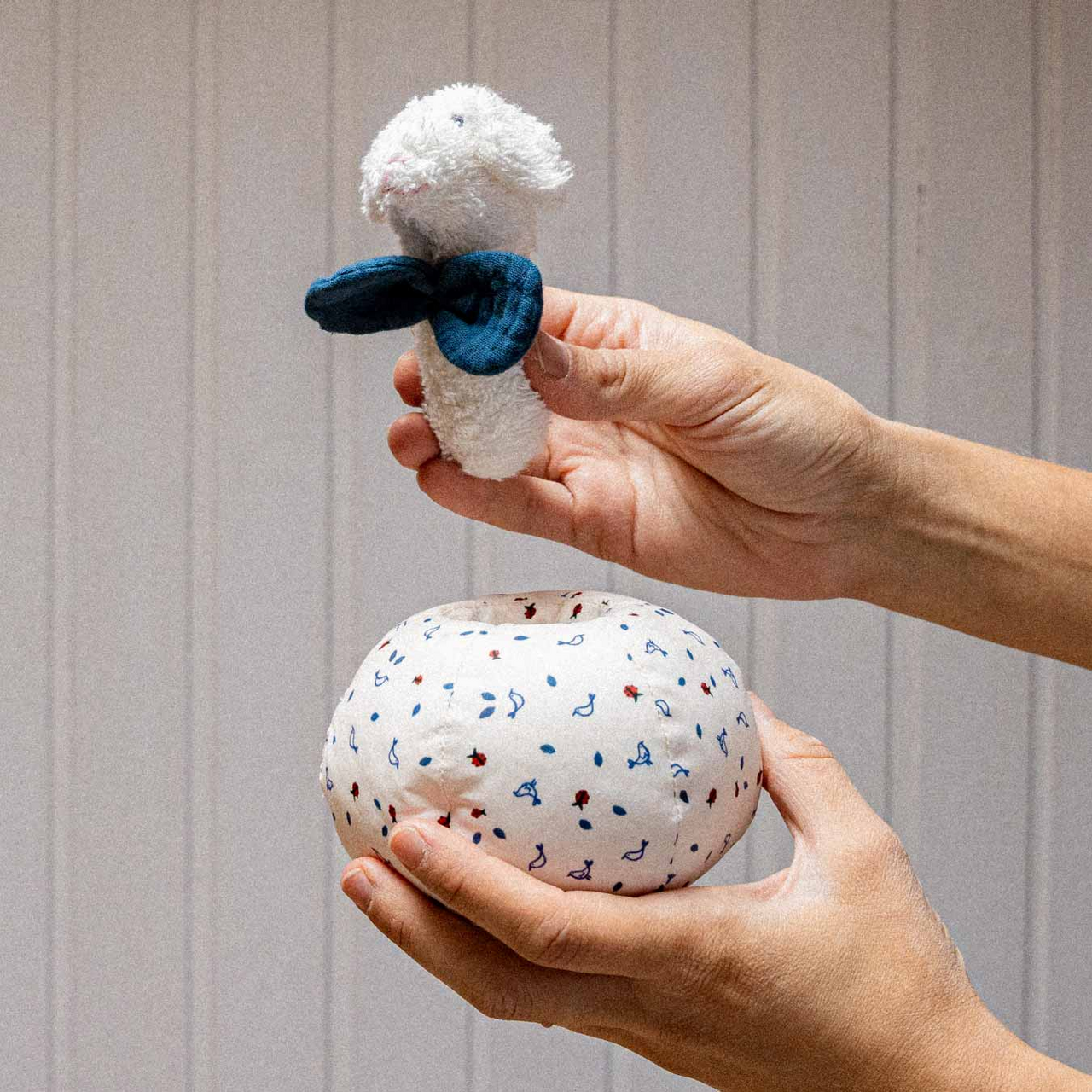 Nachhaltige kindgerechte Lamm-Rassel aus weichem, giftfreiem Material, säuglingstauglich und sicher in weiß mit blauem Schal.